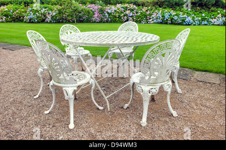 Vintage wrought iron table and six chairs in an English garden. Stock Photo