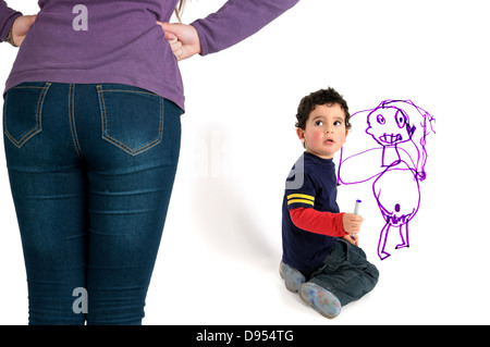 Young boy caught by his mother painting the wall Stock Photo