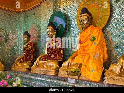 Three clothed BUDDHAS at the SHWEMAWDAW PAYA which is a 1000 years old and 114 meters high - BAGO, MYANMAR Stock Photo