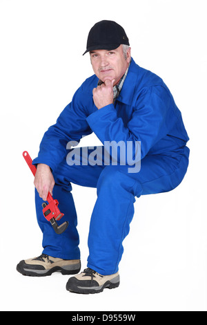 Senior plumber sat holding wrench Stock Photo