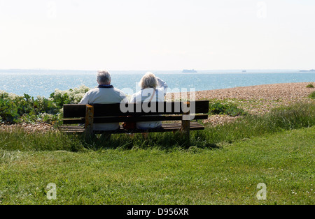 Senior couple on bench looking out to sea, The Solent at Hayling Island Stock Photo