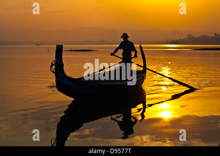 FISHERMAN ply the waters of Taungthaman Lake at sunrise - AMARAPURA, MYANMAR Stock Photo