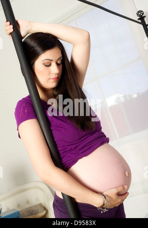 Woman expecting a baby holds canopy bed standing in front of window Stock Photo