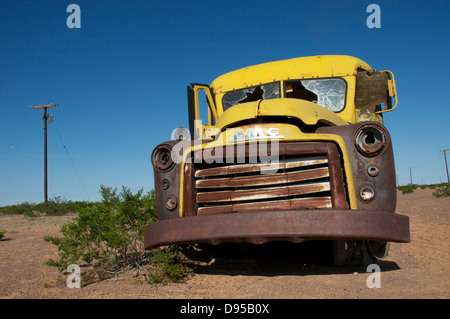 An iconic yellow US school bus lays abandoned in the deserts of Texas, USA. Stock Photo