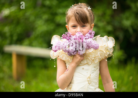 Portrait of a little girl with a bouquet of lilacs outdoors Stock Photo