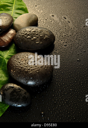wet massage stones with green leaf and water drops Stock Photo