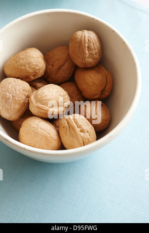whole walnuts in the shell in a bowl on a blue fabric Stock Photo