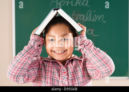 Girl With Textbook on her Head in Classroom, Baden-Wurttemberg, Germany Stock Photo