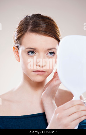 Head and Shoulders Portrait of Teenage Girl Looking in Mirror in Studio Stock Photo