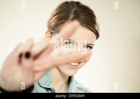 Portrait of Teenage Girl Making the Peace Sign with Her Fingers, in Studio Stock Photo