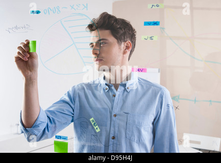 Young Man Working in an Office, Looking Through Glass Board, Germany Stock Photo