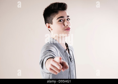 Portrait of Boy Pointing and Looking at Camera in Studio Stock Photo