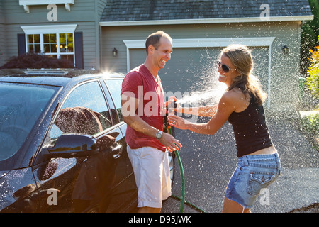 Couple washing their car in the driveway of their home on a sunny summer afternoon in Portland, Oregon, USA Stock Photo