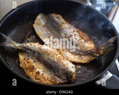 Herrings coated in freshly made gluten free breadcrumbs being fried in butter. Stock Photo
