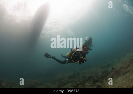 Divers descend from boat in plankton-rich water in the Lembeh Straits, Indonesia Stock Photo
