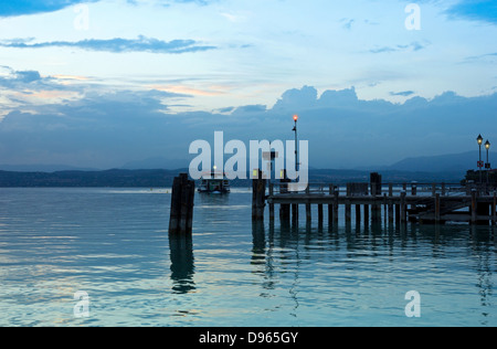 Peaceful evening on Lago di Garda in Italy, with Jetty pier in Sirmione and the last ferry boat for the day. Stock Photo