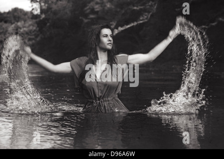 Woman splashing water out of river Stock Photo