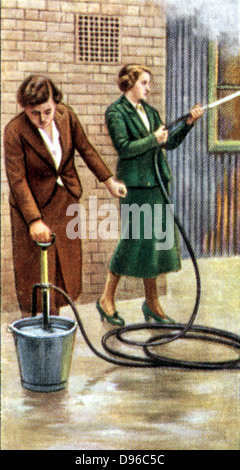Air Raid Precautions': Set of 50 cards issued by WD & H0 Wills, Britain 1938, in preparation for the anticipated coming of World War II. Women fighting fire with stirrup hand pump. Stock Photo