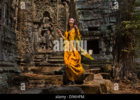 Chinese woman modelling clothes for a fashion photograph in temple ruins, Ta Prohm, Angkor temple complex. Ankor Wat Cambodia Stock Photo