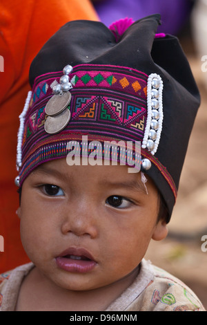 A baby girl of the AKHA tribe wears a childs headdresse made of beads, silver and hand loomed cotton - village near KENGTUNG or Stock Photo
