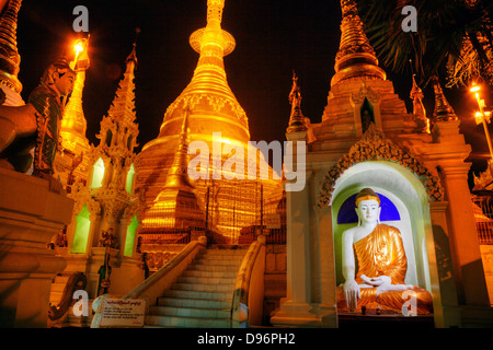 A BUDDHA STATUE and the main ZEDI of the SHWEDAGON PAGODA which dates from 1485 is gilded every year - YANGON, MYANAMAR Stock Photo