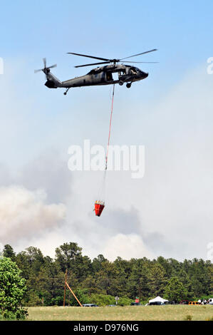 A US National Guard UH-60 Black Hawk helicopter carries water to assist in fighting the Black Forest fire June 12, 2013 in El Paso County, CO. More than 100 homes have burnt in the fire south of Colorado Springs, CO. Stock Photo