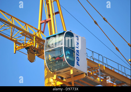 A crane operator sits in the glass cab of a tower crane above Johannesburg. Stock Photo