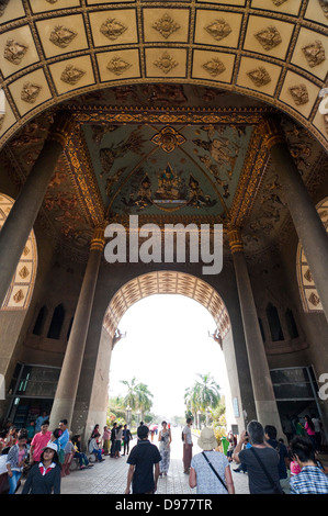 Vertical view of tourists sitting and walking through the decorated arch of the Victory Gate or Patuxai in central Vientiane. Stock Photo