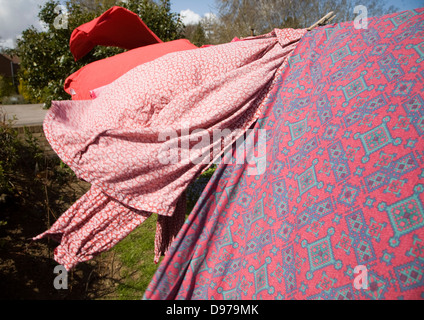 Red pink and purple clothes drying on washing line Stock Photo