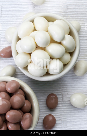 Peanuts coated with dark and white chocolate in small bowls Stock Photo