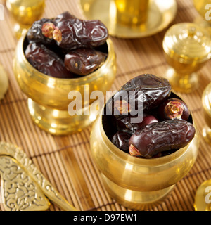 Dried date palm fruits or kurma, ramadan food which eaten in fasting month. Pile of fresh dried date fruits in golden metal bowl. Stock Photo