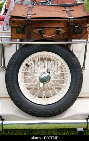 Spare wheel tire and brown leather suitcase Stock Photo