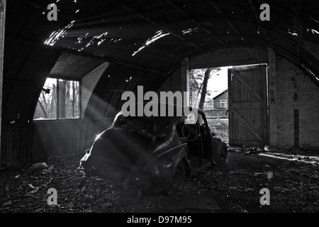 Black and white old car derelict garage with sunburst window Stock Photo