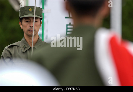 members of the Japan Ground Self-Defense Forces (GSDF) raise the Japanese flag before a live fire exercise in Japan Stock Photo