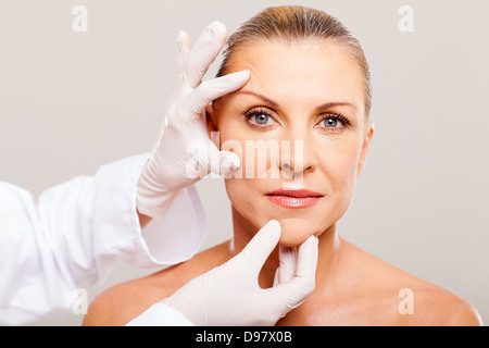 surgeon doing skin check on mid age woman before plastic surgery Stock Photo