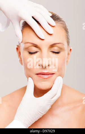 plastic surgeon checking middle aged womans face after operation Stock Photo