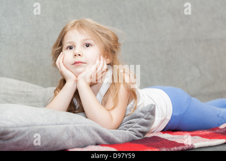 Little Caucasian girl dreaming lying on the couch Stock Photo