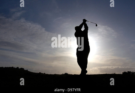 Golf player taking a shot at sunset