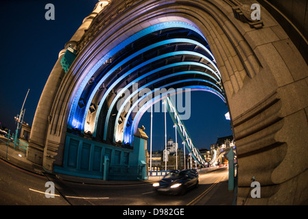Tower Bridge Illuminated Archway London United Kingdom / LONDON, United Kingdom — Tower Bridge, a Grade I listed landmark, is illuminated at night, showcasing its distinctive neo-Gothic architecture. Completed in 1894, the combined bascule and suspension bridge spans the River Thames, connecting the borough of Tower Hamlets on the north bank with Southwark on the south. Its iconic twin towers and suspended walkways are highlighted by an elaborate lighting system. The bridge, named after the nearby Tower of London, remains a vital river crossing and a major tourist attraction. Stock Photo