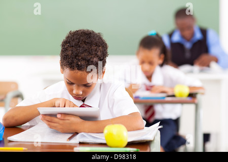 cute elementary schoolboy using a tablet computer in classroom Stock Photo