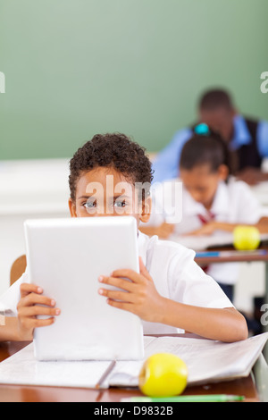 cute male elementary school student using tablet computer in classroom Stock Photo
