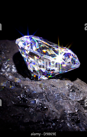 Single cut diamond on a piece of coal to symbolise them both being carbon based, studio shot taken against a black background. Stock Photo