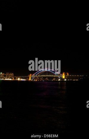 A night time photograph of the Sydney Harbour Bridge, lit up with colourful lights for Vivid. Stock Photo