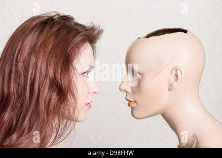 Young red haired woman in her 20s looking at broken mannequin Stock Photo
