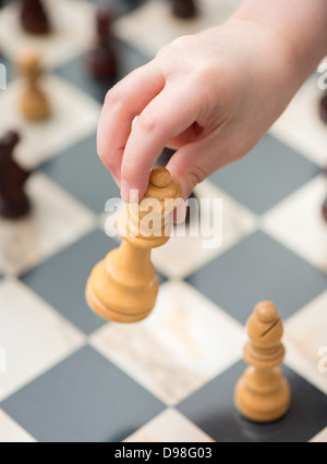 Hand of small girl 3-4 yrs moving chess piece (white queen) Stock Photo