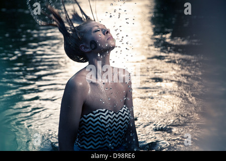 Woman throwing hair back in body of water Stock Photo