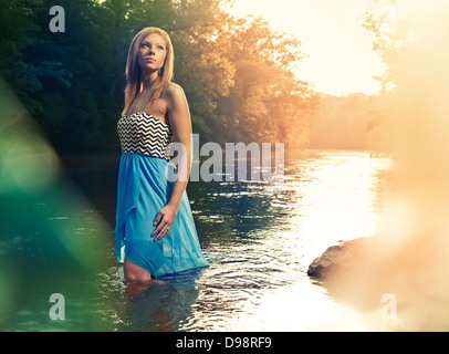 Woman in blue dress walking in river during sunset