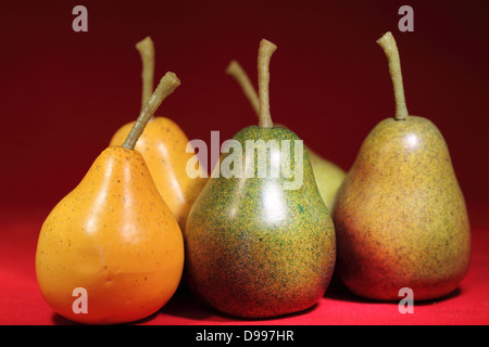 Five pears, two yellow and three green on red backdrop. Focus on three front pears. Stock Photo