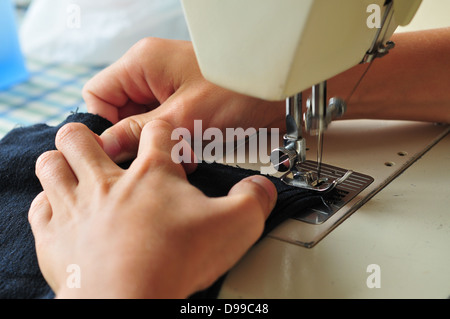 Sewing machine detail - needle, thread guide, presser foot, throat plate and feed dogs in action Stock Photo