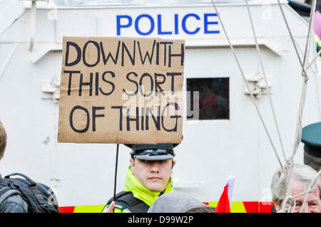 Belfast, Northern Ireland. 15th June 2013. A handwritten banner is held up in front of a policeman saying 'Down with this sort of thing', a reference to a protest from an episode of 'Father Ted'. It looks as if the police officer is holding the sign.  Credit:  Stephen Barnes/Alamy Live News Stock Photo